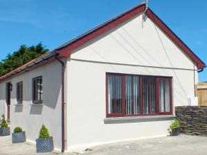 a white house with a window and a stone wall at Swallows Retreat in Hartland