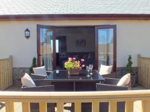 a patio with a table and chairs on a deck at Swallows Retreat in Hartland +14 photos