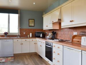a kitchen with white cabinets and white appliances at Bugatti House in Bosbury