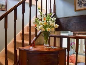 a vase of flowers on a table next to stairs at Bugatti House in Bosbury