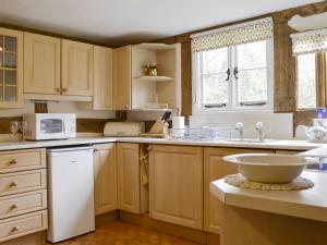 a kitchen with wooden cabinets and a white appliance at Hollywall Croft in Stoke Prior