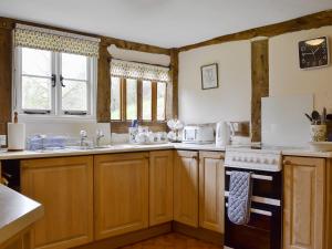 a kitchen with wooden cabinets and a stove top oven at Hollywall Croft in Stoke Prior