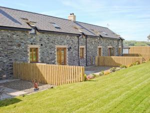 a stone house with a wooden fence in a yard at Bwthyn Celyn-Oa6 in Ystrad Meurig