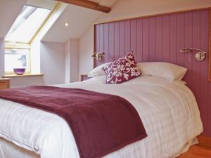 a bedroom with a large bed with a purple wall at Bwthyn Celyn-Oa6 in Ystrad Meurig