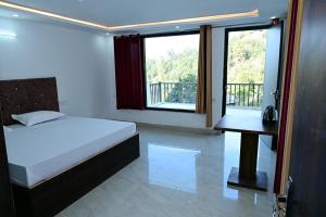 a bedroom with a bed and a desk and windows at Shanti Residency Ramgarh in Rāmgarh