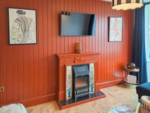 a living room with a red wall with a fireplace at The Lobster Pot in Shotley Gate