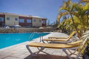 a swimming pool with lounge chairs next to a resort at Memorable Holidays With Your Family in Maspalomas