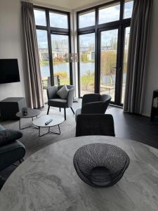 a living room with a table and chairs and windows at Casa-MiU am Wasser - Olburgen - perfekt für Familien - mit Freibad, Sauna, Restaurant und Spielplatz in Olburgen