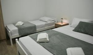 two beds in a hotel room with towels on them at Nanchev Apartments in Gevgelija