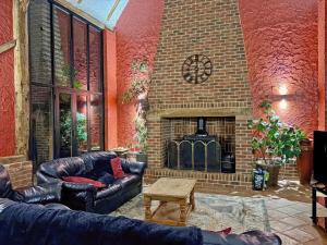 a living room with leather furniture and a brick fireplace at Clamp Farm Barn in Stowmarket