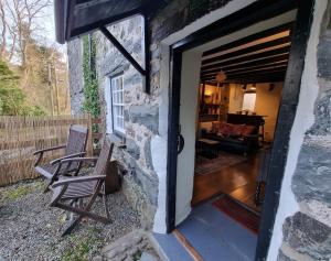 a door leading into a stone house with two chairs at River Cottage in Llanbedr