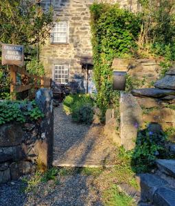 an entrance to a stone house with a sign at River Cottage in Llanbedr +5 photos