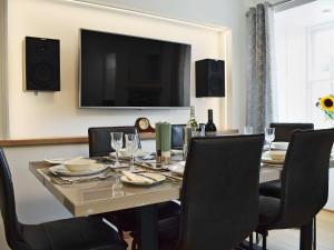 a dining room with a table with chairs and a television at Waterloo Farm House in Bankfoot