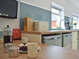 a kitchen with a wooden table with cups on it at Waterloo Farm House in Bankfoot