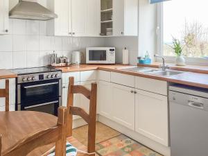 a kitchen with white cabinets and a table and a microwave at Keepers Cottage - Uk51549 in Kirktown of Auchterless