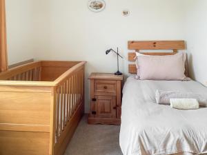 a bedroom with a crib and a bed with a dresser at Keepers Cottage - Uk51549 in Kirktown of Auchterless