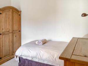 a bedroom with a bed and a wooden cabinet at Keepers Cottage - Uk51549 in Kirktown of Auchterless +4 photos
