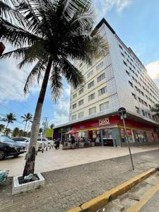 a palm tree in front of a large building at Apto completo,1 dorm, pé na areia na Cidade Praia Grande, praia mirim in Praia Grande