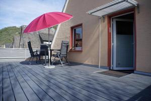 a patio with a table and chairs and a pink umbrella at Ferienwohnungen Reinhilde - Litzig in Traben-Trarbach