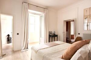 a white bedroom with a bed and a dog in it at Elegant Seafront Apartment in Ostia in Lido di Ostia