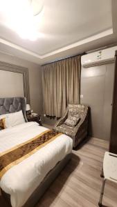 a bedroom with a large bed and a chair at العنوان للشقق المخدومة ALanwaan of the units served in Dammam