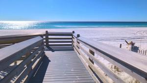 a wooden boardwalk leading to a beach with the ocean at Gulf Balcony - Boutique Comforts & 2 King Suites in Fort Walton Beach