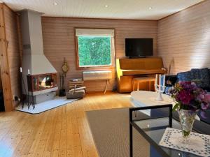 a living room with a fireplace and a piano at Swedish cottage near ocean in Norrtälje