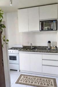 a white kitchen with a sink and a microwave at Apê estiloso e funcional no coração da cidade in Porto Velho +21 photos