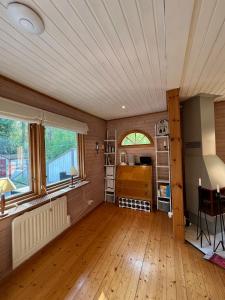 a living room with a wooden floor and windows at Swedish cottage near ocean in Norrtälje