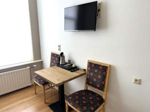 pokój ze stołem i krzesłami oraz telewizorem na ścianie w obiekcie Hotel Corel w Scheveningen