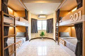 a dorm room with bunk beds and a potted plant at KPOP Hostel in Karon Beach