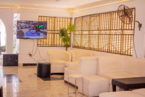 a waiting room with white chairs and a flat screen tv at Beulah House Lounge in Ibadan