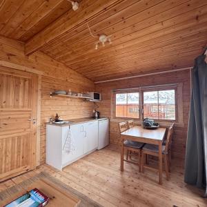 a kitchen with a table in a wooden cabin at Armuli in Reynistaður