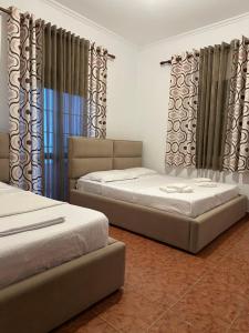 two beds in a room with curtains at Guesthouse Enea in Durrës