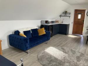 a living room with a blue couch and a kitchen at Loft apartment in Herstmonceux