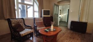 a living room with two chairs and a table and a tv at Anna Vendégház in Kápolnásnyék