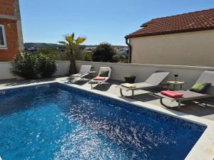 a swimming pool with lounge chairs and a table next to a building at Vila VivaVir with 2x E-Scooter, private Pool & Grill in Vir