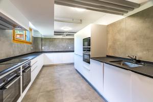 a kitchen with white cabinets and black counter tops at Gästehaus auf Camping Grächbiel in Grächen