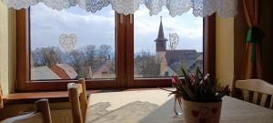 a room with a table and a large window with a church at Ubytovanie Gerlachov - Anna Bajzikova in Svätý Jur