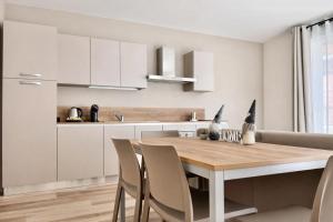 a kitchen with white cabinets and a wooden table and chairs at Nuovo appartamento in centro a Darfo Boario Terme in Boario Terme