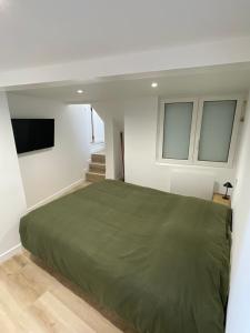 a bedroom with a green bed and a tv at Belle escale by LV in Dieppe
