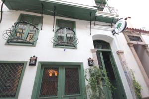 a white building with green doors and windows at Defne Pansiyon Ayvalık in Ayvalık
