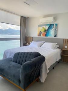 a bedroom with a large bed with a blue couch at Vilella Vista Bela in Angra dos Reis