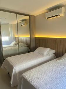 two beds in a hotel room with a mirror at Vilella Vista Bela in Angra dos Reis