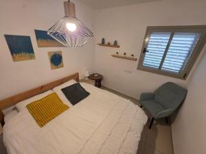 a bedroom with a bed and a chair and a window at Tavor view נוף תבור in Daverat