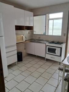 a kitchen with white cabinets and a stove top oven at Apartamento em Pelotas Centro in Pelotas