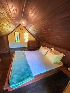 a large bed in a room with a wooden ceiling at Chalé Espaço Raiz de Lumiar in Nova Friburgo