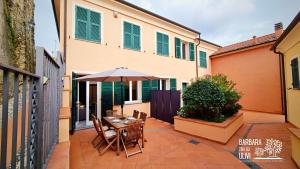 a patio with a table and an umbrella at Barbara tra gli Ulivi in Diano Arentino
