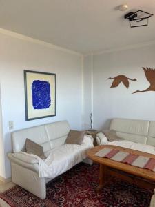 a living room with two white couches and a coffee table at Haus-am-Deich in Wittdün