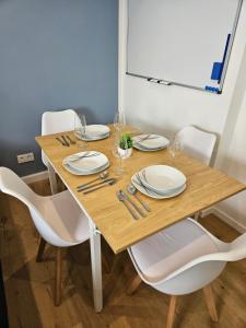 a wooden table with white plates and glasses on it at Stilvolle Wohnung mit Balkon & Parkplatz in Moers - Ideal für Business, Familien und Monteure nahe Düsseldorf in Moers